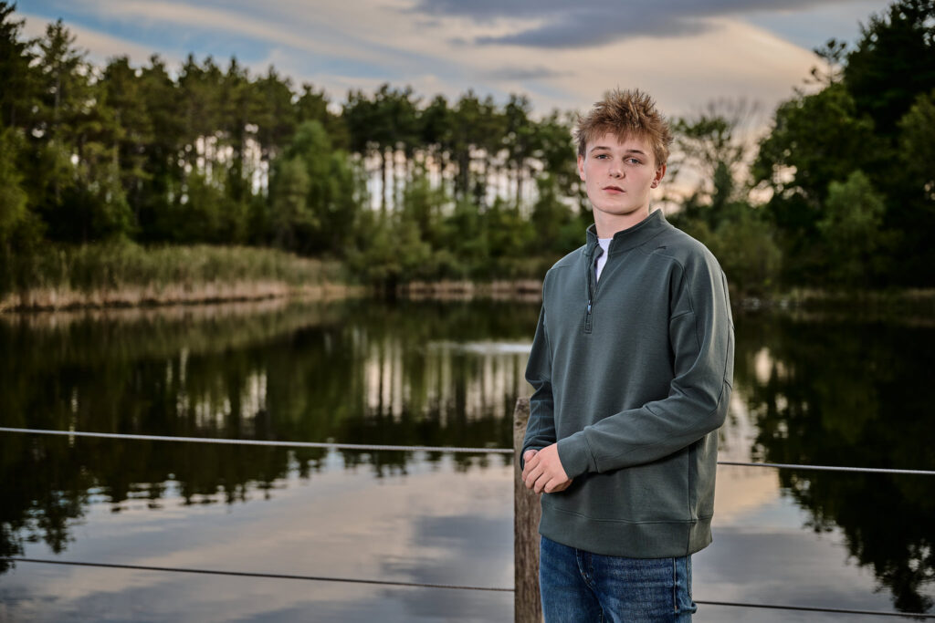 senior boy in jester park, granger, iowa in front of a pond