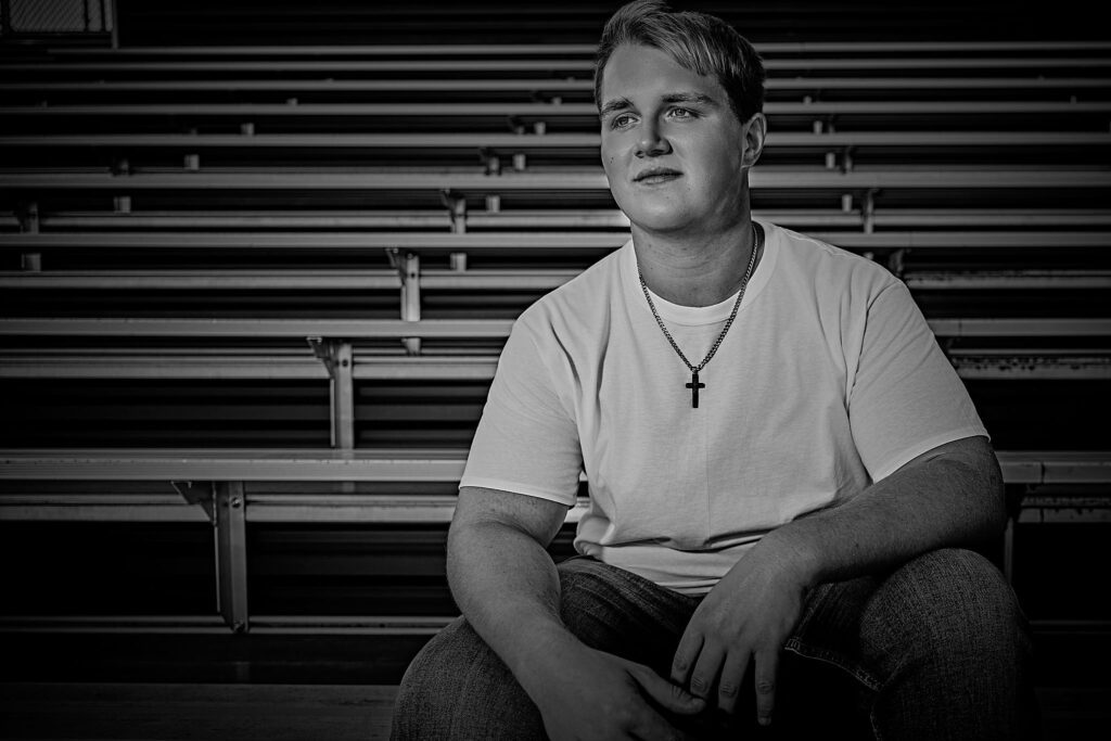 Senior guy sitting on bleachers, looking into the distance