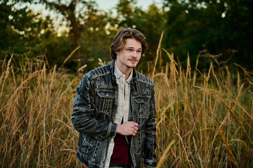 Senior guy at Cottonwood Park walking through tall grass during fall